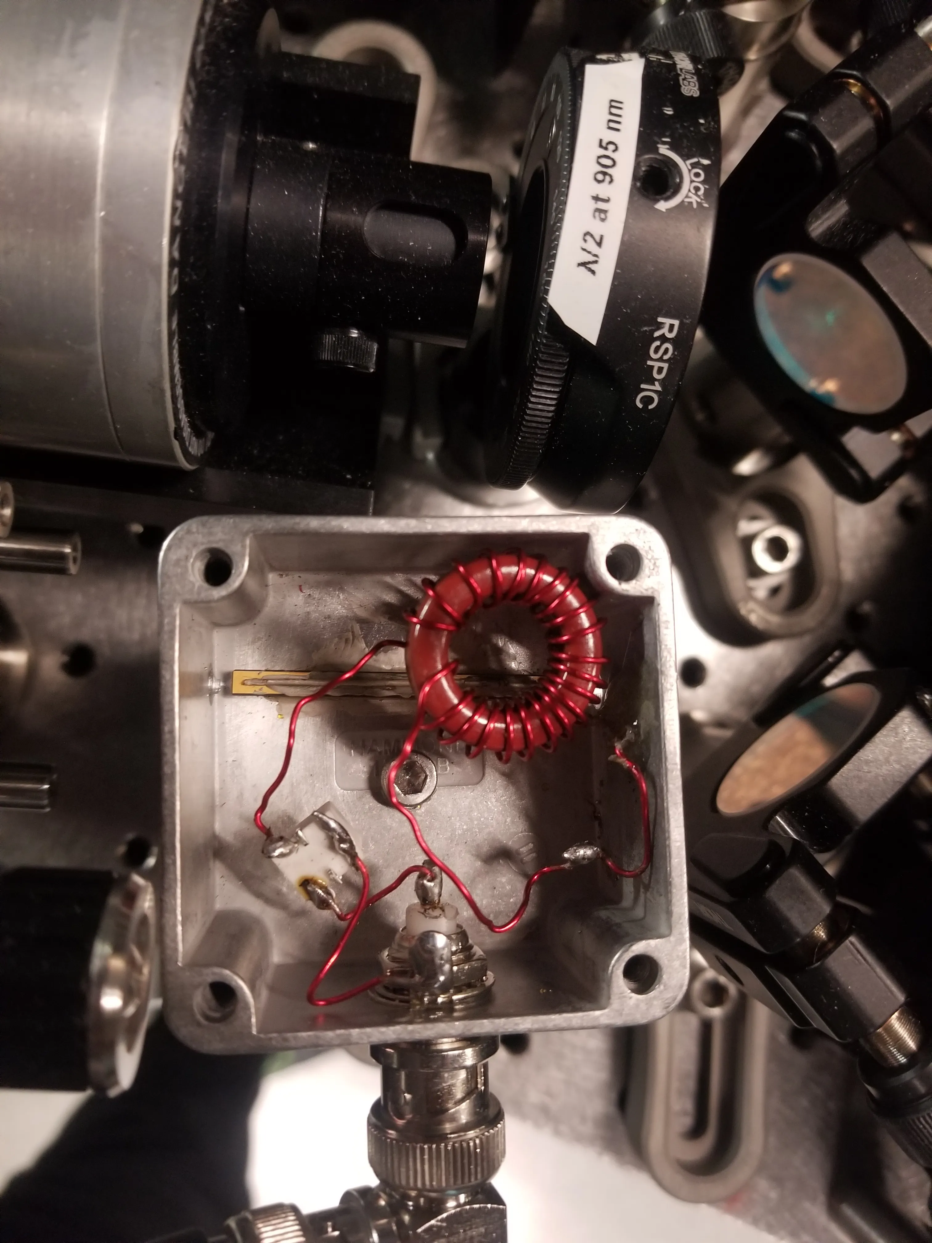 A resonant EOM and its RF matching network, with a waveplate and Faraday isolator on the bench beyond.