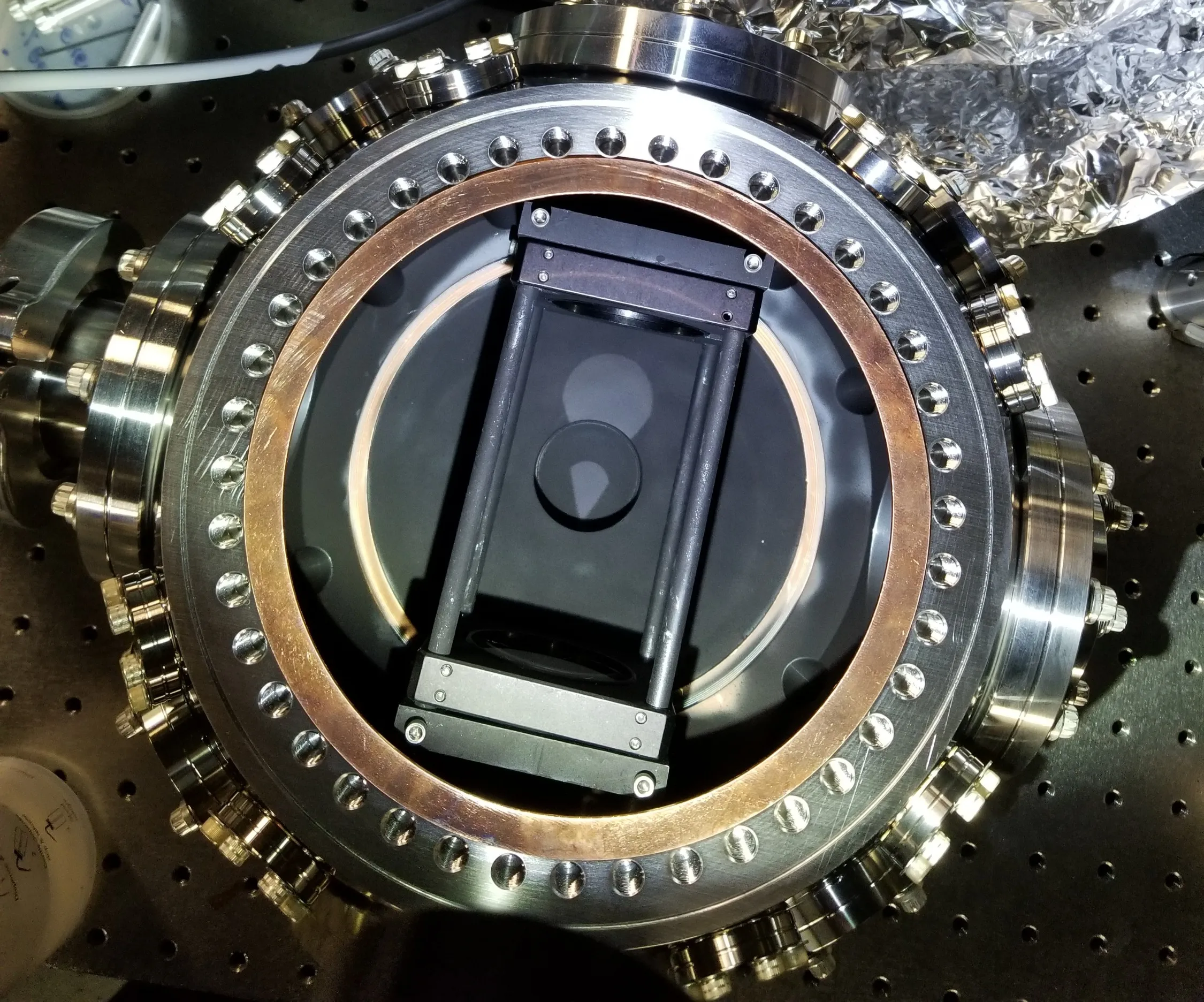 The in-vacuum fluorescence-collection optics mounted inside the UHV chamber (copper gasket visible) — the built version of the assembly designed below.
