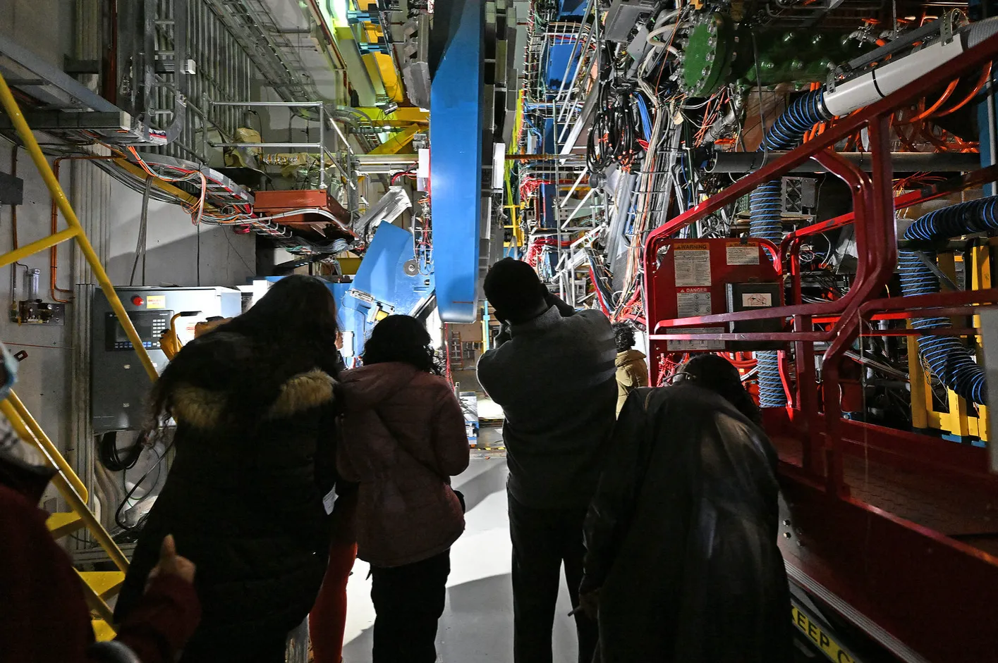 The scale of it — researchers dwarfed by the detector and its cabling in the RHIC experimental hall at Brookhaven.